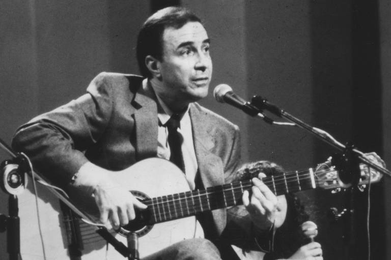 João Gilberto sentado com violão e microfone