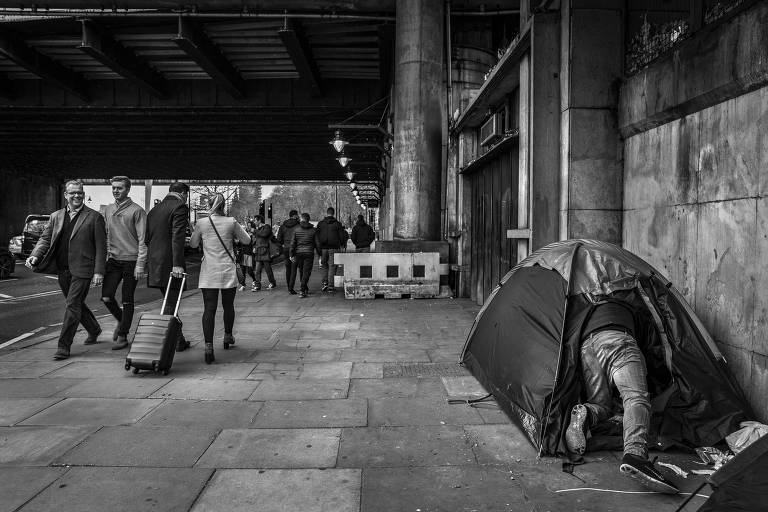 Morador de rua entra na sua barraca montada em uma calçada próxima a estação do metrô, em Londres