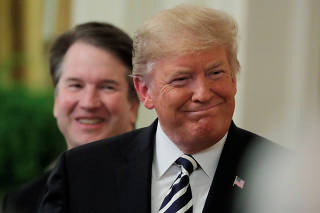 FILE PHOTO: U.S. President Donald Trump smiles next to U.S. Supreme Court Associate Justice Brett Kavanaugh as they participate in a ceremonial public swearing-in in the East Room of the White House in Washington