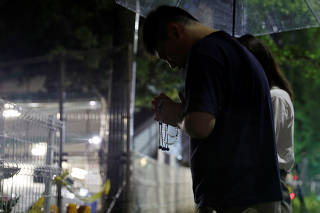A Chinese animation fan who lives in Osaka mourns for the victims in front of Kyoto Animation's studio building which was burnt out by arson attack in Kyoto