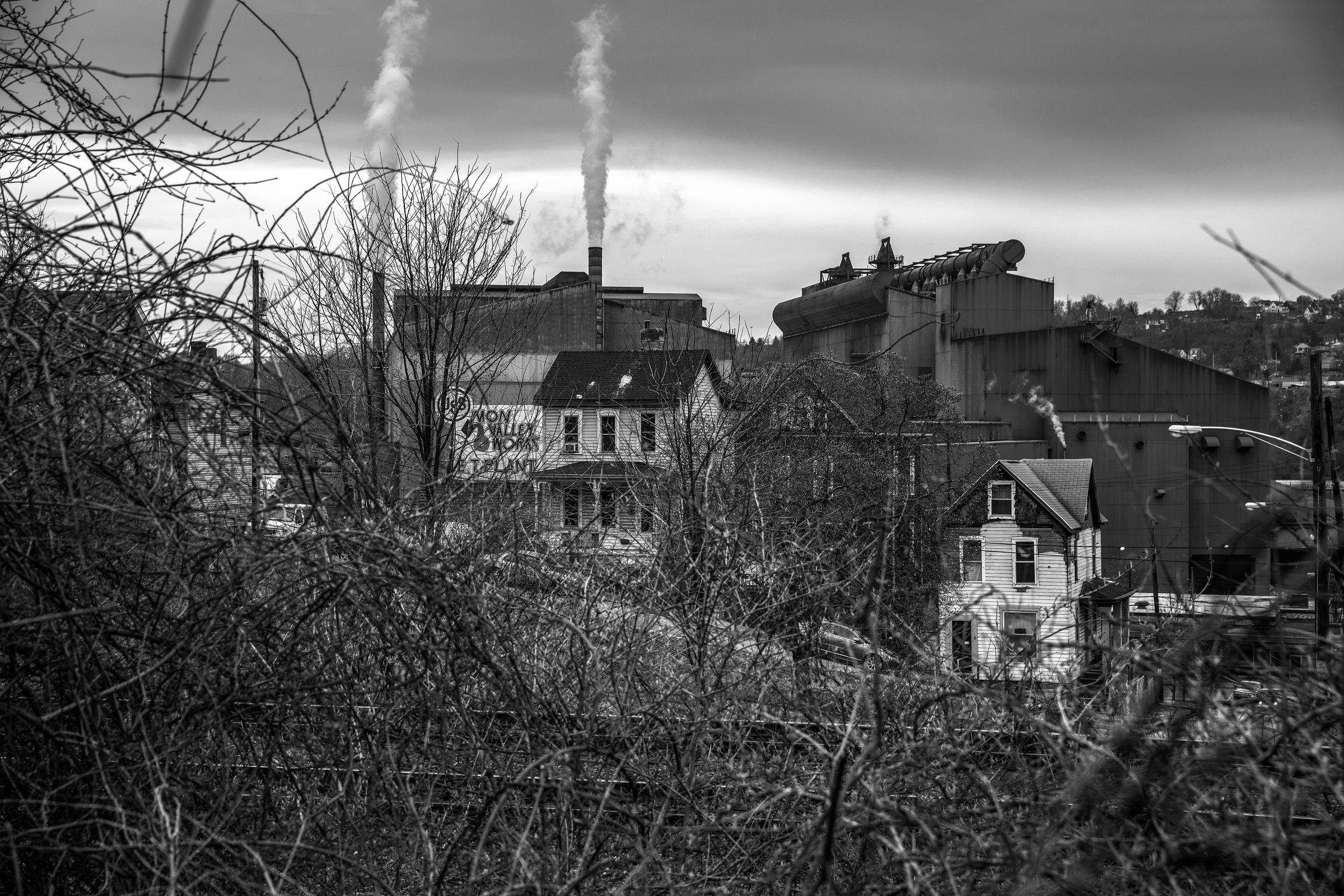 Casas en mal estado en Braddock, Pensilvania, con las chimeneas de la planta de acero Edgar Thomson al fondo