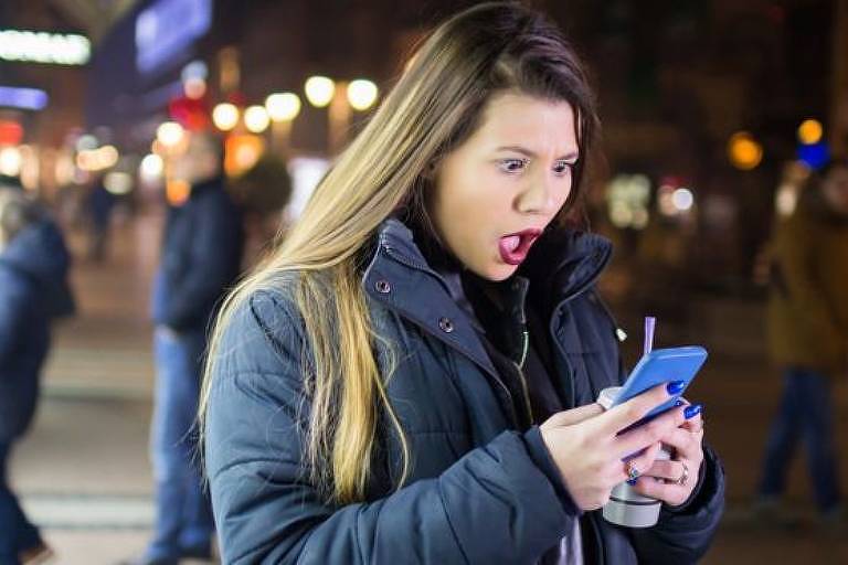 mulher chocada ao olhar preço no celular