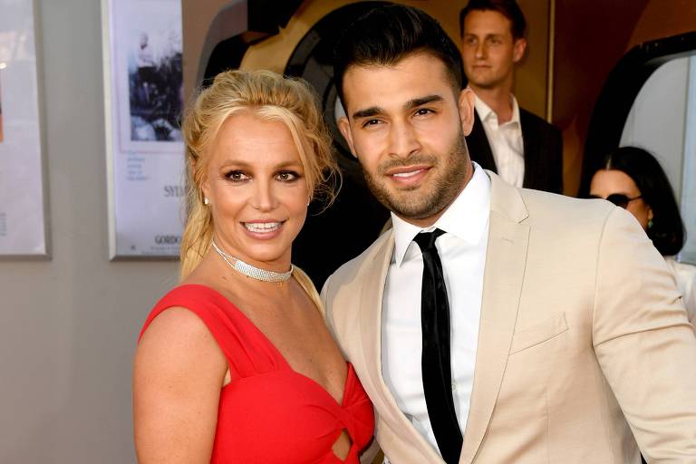Britney Spears, com vestido vermelho, e o namorado Sam Asghari, com terno cinza