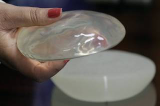 An employee of the Ministry of Health displays a silicone gel breast implant, manufactured by the now-defunct French firm PIP, during a news conference in San Jose