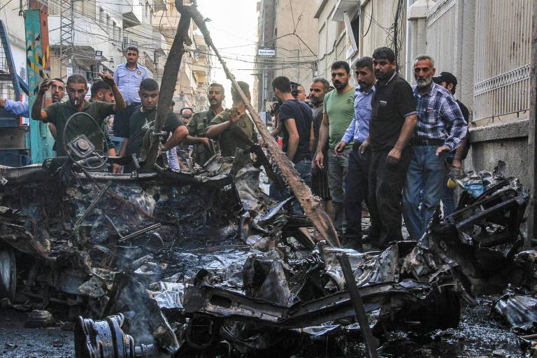 Pessoas ao lado de carro-bomba que explodiu na cidade síria de Qamishli, onde o americano Sam Goodwin foi detido