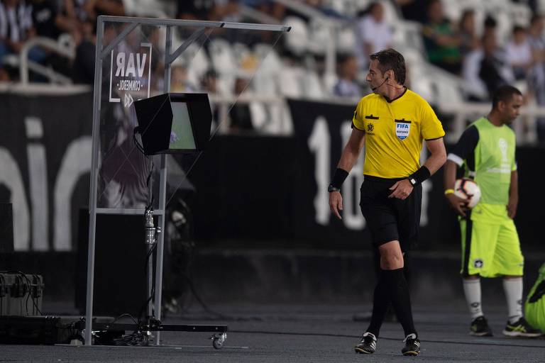 O árbitro Raphael Claus checa o VAR durante partida entre Botafogo e Atlético-MG, realizada no estádio Nílton Santos