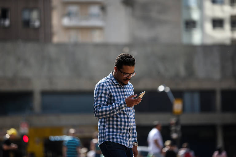Paulistanos usam celular na região central de SP; cerca de um terço dos registros eletrônicos de roubos e furtos desses aparelhos é rejeitado