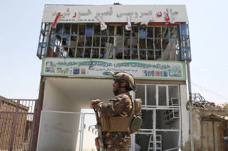 A member of Afghan security forces keeps watch at the site of a car bomb blast in Kabul