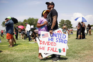 People embrace while holding placards during a rally against the visit of U.S. President Donald Trump after last weekend's shooting at a Walmart store, in El Paso