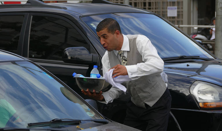 Ambulante elegante faz sucesso vendendo água para motoristas na esquina das avenidas Rebouças e Brasil, na zona sul de São Paulo