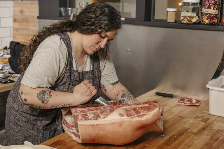 A açougueira Lauren Garaventa corta costelas de carne em seu restaurante, The Ruby Brink, na ilha de Vashon