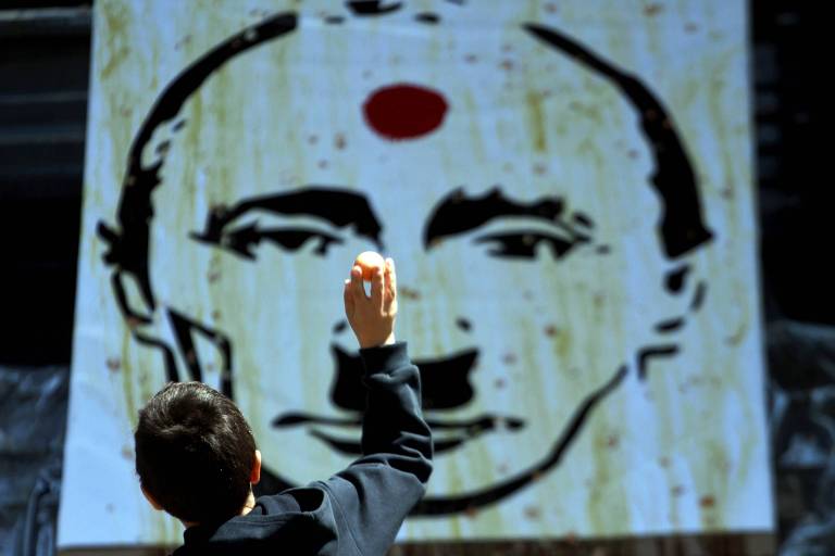 Menino joga ovo contra imagem do presidente Vladimir Putin caracterizado como Hitler, em Kiev, na Ucrânia 