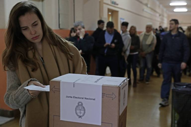 Eleitora deposita, em Buenos Aires, seu voto nas prévias realizadas neste domingo (11), na Argentina
