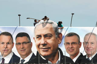FILE PHOTO: Labourers work on hanging up a Likud election campaign banner depicting Israeli Prime Minister Benjamin Netanyahu with his party candidates, in Jerusalem