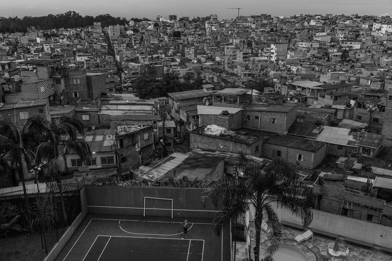 foto em preto e branco mostra contraste aéreos entre condomínio de luxo, onde uma mulher joga tênis em uma quadra, e a favela ao fundo 