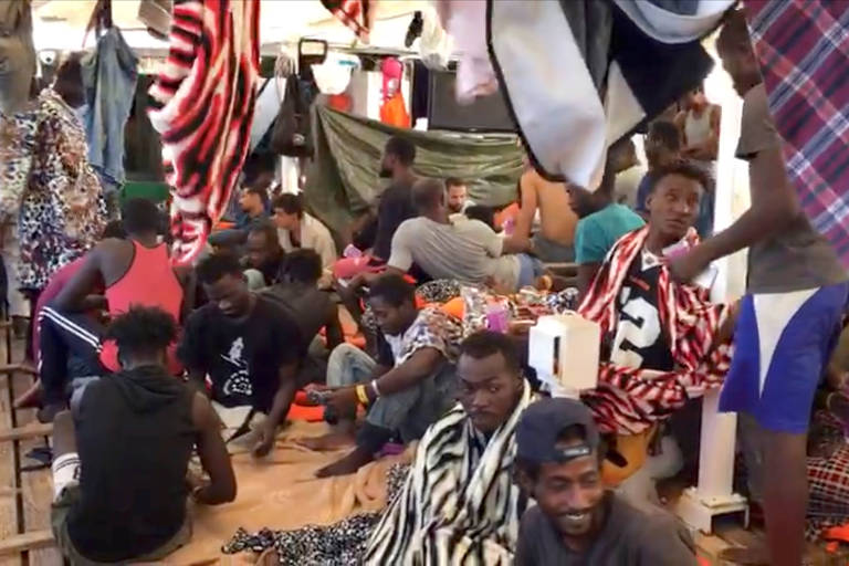 Imagem retirada de um vídeo mostra migrantes a bordo do navio espanhol de resgate Open Arms, parado próximo à costa italiana
