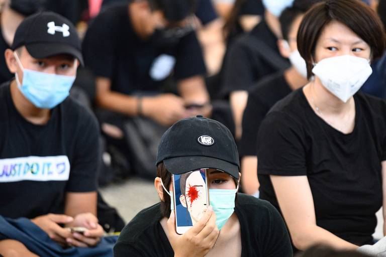 Manifestante segura celular com imagem em referência a garota que sofreu agressão no olho durante protesto em Hong Kong