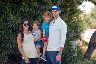 Michael Phelps and his wife, Nicole, who is expecting their third child, hold their sons, Beckett, 1, left, and Boomer, 3, in their neighborhood in Paradise Valley, Ariz., Aug. 17, 2019. (Caitlin O'Hara/The New York Times)
