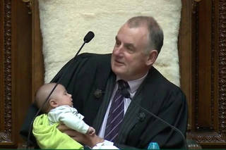 Screenshot from a Parliament broadcast of New Zealand Speaker Trevor Mallard holding a Member of Parliament?s baby during a parliamentary session in Wellington