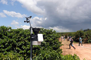 A weather station is seen as workers enter a coffee plantation in Sao Sebastiao do Paraiso