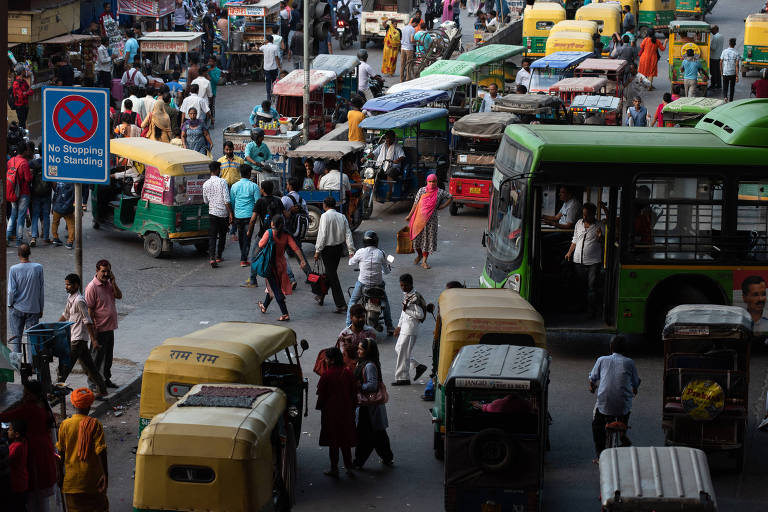 Pedestres e veículos lotam uma rua em Nova Déli