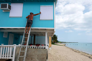 A man boards up a window of a beach house in the tourist zone of El Combate