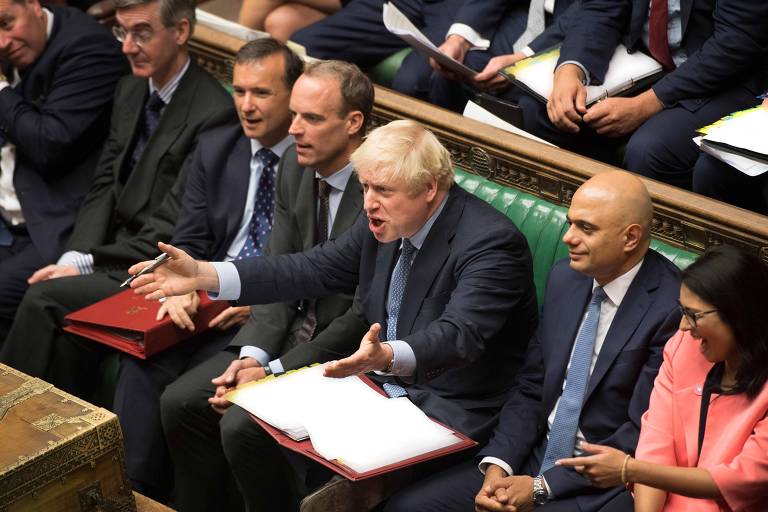 Ao lado de aliados, o premiê Boris Johnson gesticula durante o debate no Parlamento nesta quarta (4) 