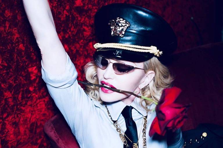 Madonna fantasiada de policial com uma rosa na boca
