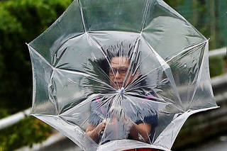 A woman using an umbrella struggles against a heavy rain and wind caused by Typhoon Faxai in Tokyo