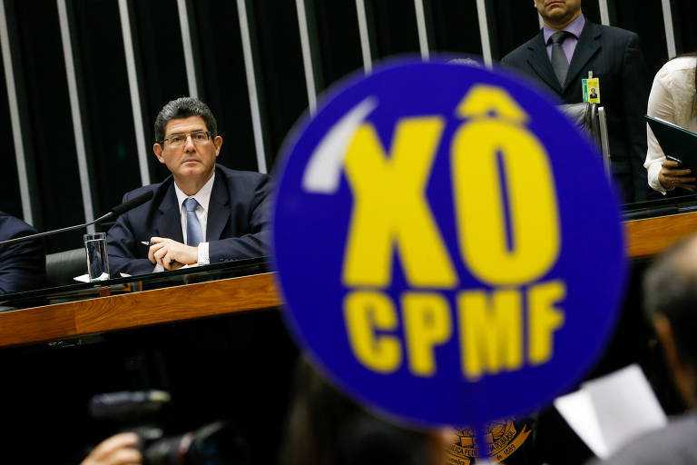 Em outubro de 2015, durante o segundo governo Dilma, o então ministro da Fazenda, Joaquim Levy, propôs a volta da CPMF para recompor às já prejudicadas contas públicas, o que foi rechaçado pelo Congresso. A oposição protestou com cartazes contra o imposto. Na foto, a ex-presidente cumprimenta o então presidente da Câmara dos Deputados Eduardo Cunha (PMDB-RJ). Ao fundo, o então ministro da Fazenda, Joaquim Levy
