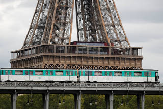 An elevated Metro passes over a bridge next to the Eiffel Tower in Paris on the eve of a strike against pension reform plans