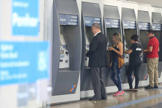 Clientes usam caixa automático, dentro de agência da Caixa Econômica Federal