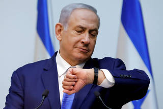 FILE PHOTO: Israeli Prime Minister Benjamin Netanyahu looks at his watch before delivering a statement at the Knesset, Israel's parliament, in Jerusalem