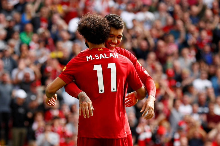 Salah comemora com Firmino o terceiro gol do Liverpool contra o Newcastle, no Campeonato Inglês, no sábado (14)