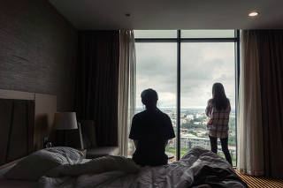Kim Ye-na, 23, left, and Lee Jin-hui, 20, two North Korean women who were forced to perform cybersex in China, look out from their hotel room in Vientiane, Laos, on Aug. 22, 2019. (Adam Dean/The New York Times)