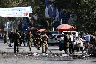 Afghan security forces remove the remains of bodies from the site of a blast in Kabul