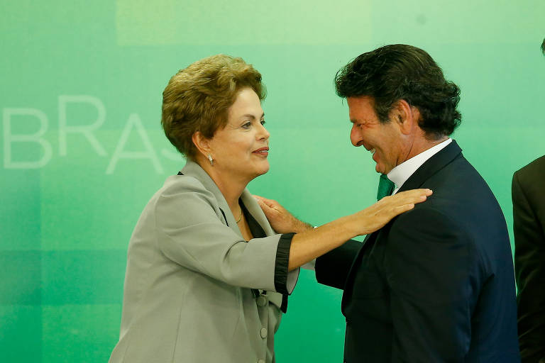 Dilma aparece cumprimentando Fux com a mão sobre seu ombro esquerdo. Ambos estão de lado para a câmera e aparecem da cintura para cima. Ela veste paletó verde-claro. Fux veste terno preto, com gravata verde.