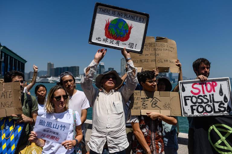 Em Hong Kong, manifestantes seguram cartazes contra exploração de combustíveis fósseis e o aquecimento global