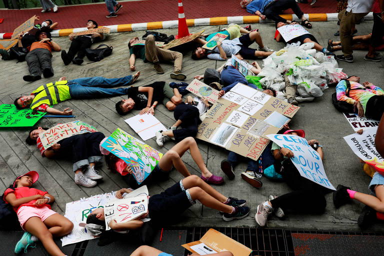 Em Bancoc, na Tailândia, ativistas ambientais fingem-se de mortos, no chão, para alertar sobre a crise global do clima