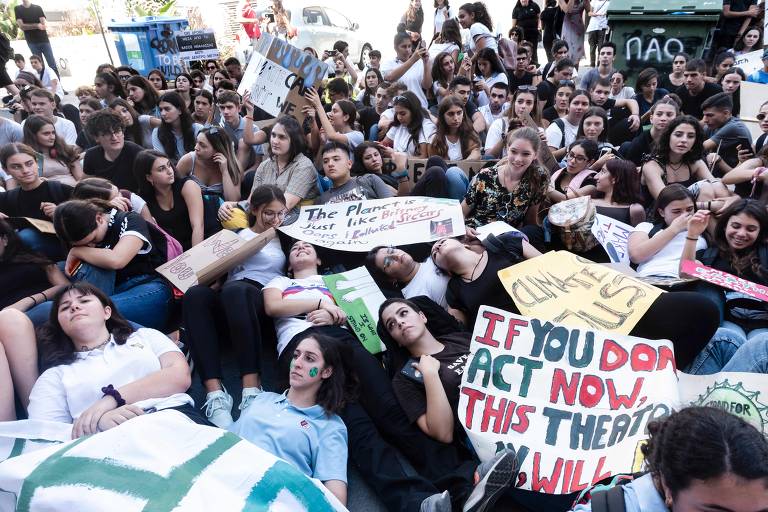 Em Chipre, estudantes e famílias cipriotas deitam e sentam no chão para participarem de protesto contra as mudanças climáticas na capital Nicósia