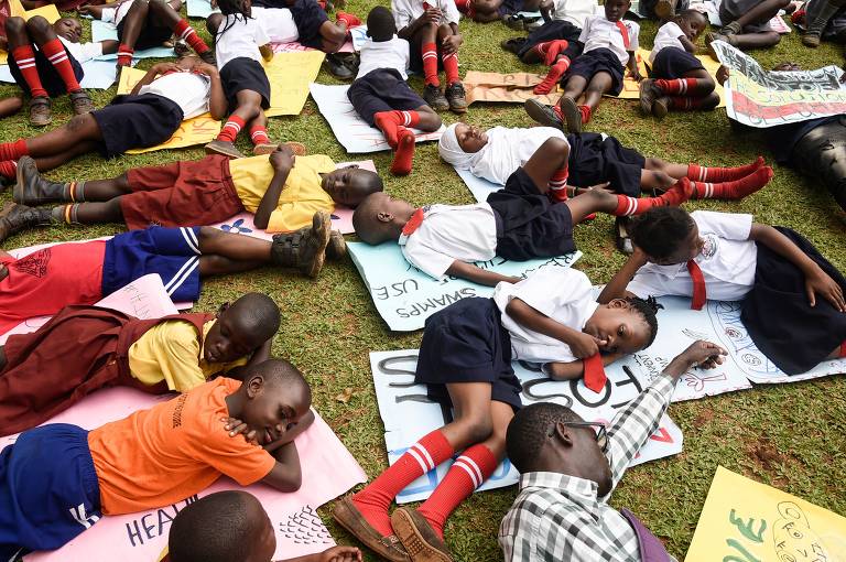 Em Uganda, crianças de escola se deitam na grama como parte de ato contra as mudanças climáticas