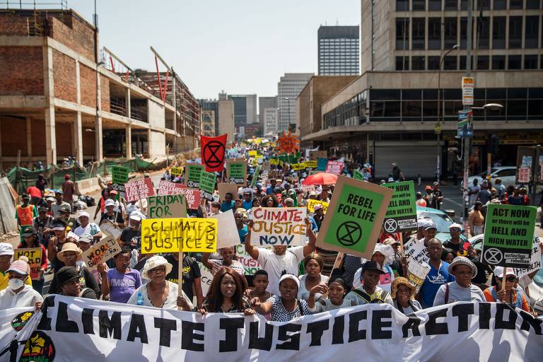 Em Joanesburgo, na África do Sul, manifestantes caminham pelas ruas da cidade com grandes faixas pedindo providências contra as mudanças climáticas