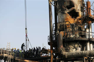 Workers are seen at the damaged site of Saudi Aramco oil facility in Abqaiq