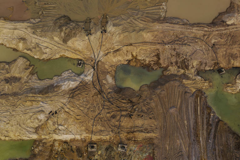 Vista aérea mostra água em cor verde ao lado de solo escavado, em tons marrons