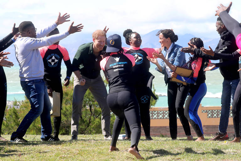 Príncipe Harry e Meghan dançam com integrantes da ONG Waves for Change na praia de Monwabisi, Cidade do Cabo