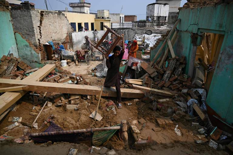 Sobrevivente do terremoto carrega pertences em meio aos escombros em Mirpur, na parte da Caxemira administrada pelo Paquistão