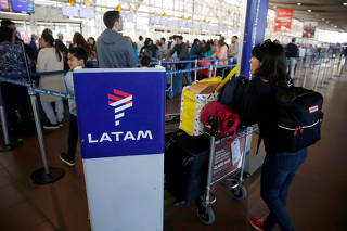FILE PHOTO: Passengers wait to check in for their flights at the departure area of Latam airlines inside of the Commodore Arturo Merino Benitez International Airport in Santiago