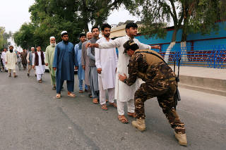 An Afghan security force officer inspects voters during the presidential election in Jalalabad, Afghanistan