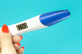 Woman hand holding digital pregnancy test isolated on blue. The pregnancy test screen with no word.