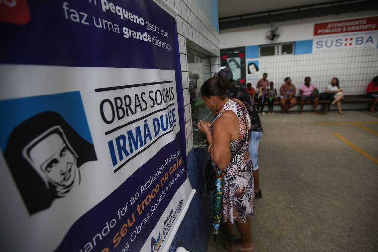 Paciente em frente à cartaz com Irmã Dulce espera por atendimento no Hospital Santo Antônio, das Obras Sociais Irmã Dulce, em Salvador, na Bahia